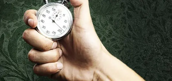 close up of a hand with a stopwatch on a green background