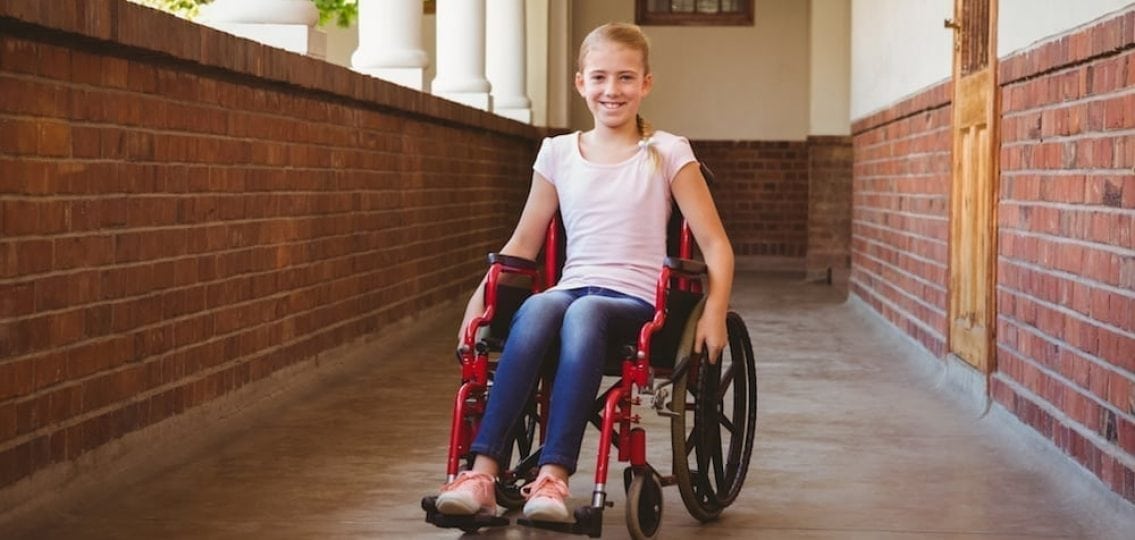 teen girl with spina bifida in wheelchair in a hallway
