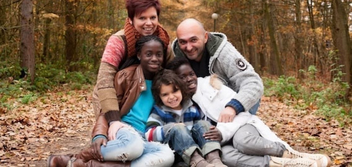 interracial family sitting outside in the fall and smiling