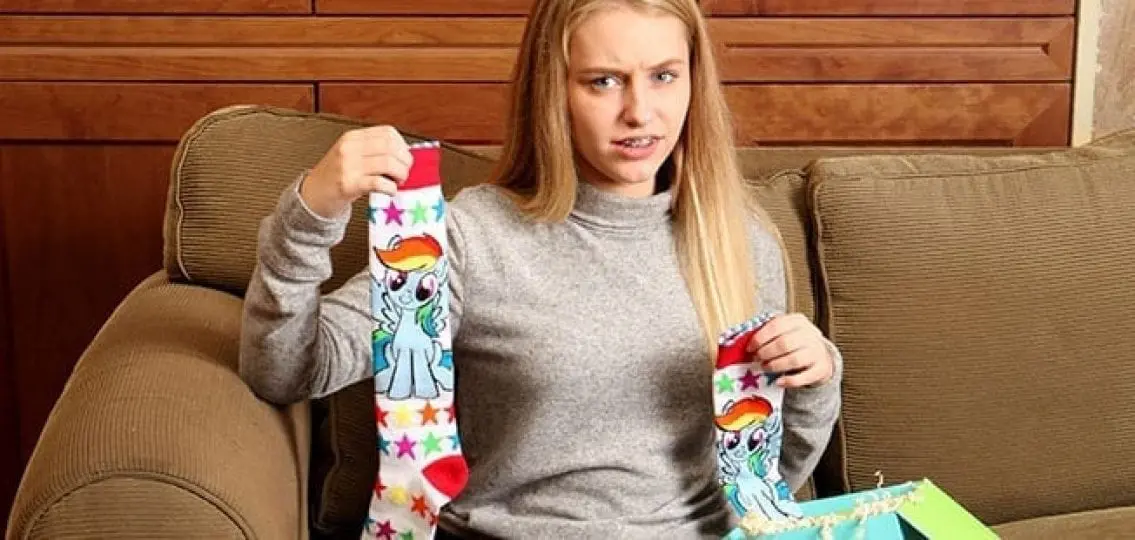disappointed teen girl holding my little pony socks and an open present box