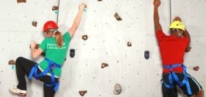 teenagers climbing a rock wall wearing helmets