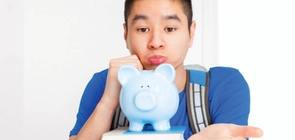 sad teenage boy with a blue piggybank holding his hand out for money