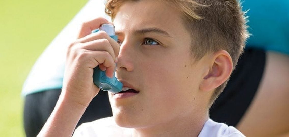 teenage boy using an inhaler for his asthma