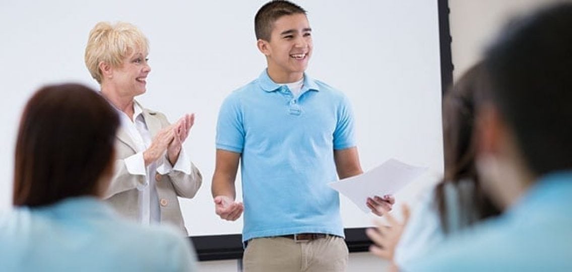 a teen boy giving a presentation in a classroom