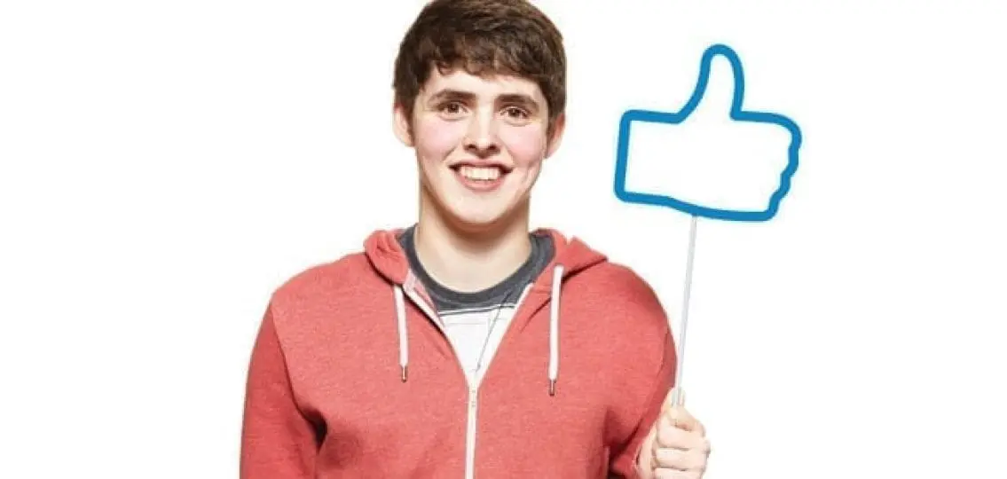 teen boy holding a sign with the facebook like symbol on it