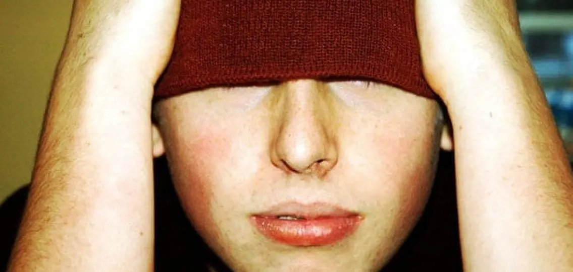 upset teen boy hiding his face with fabric
