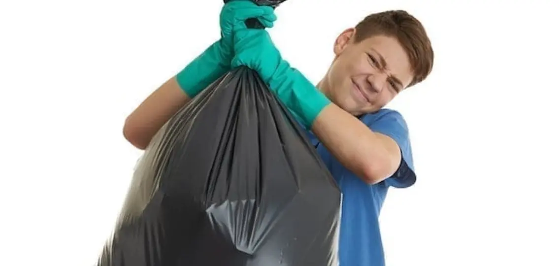 teen boy carrying large trash bag