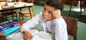 frustrated middle school boy working on the psat in the library