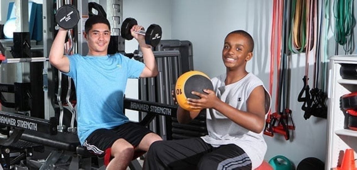 teen boys exercising in a gym and smiling