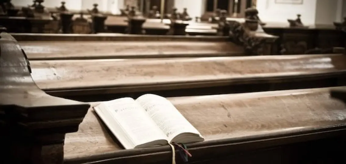 an empty church with an open bible on a pew