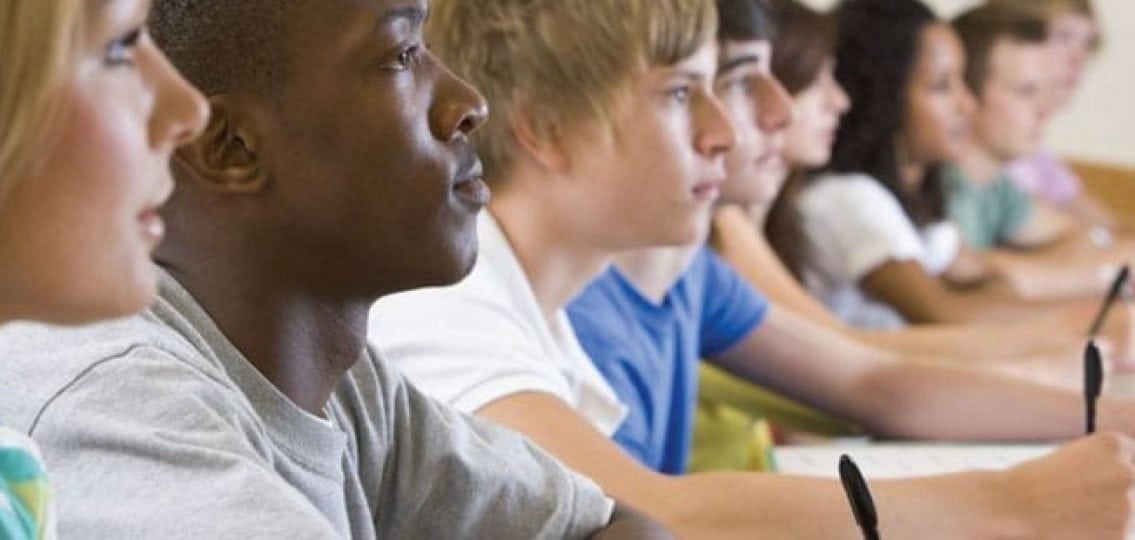 row of teenagers taking a test one teenager is black and the rest are white
