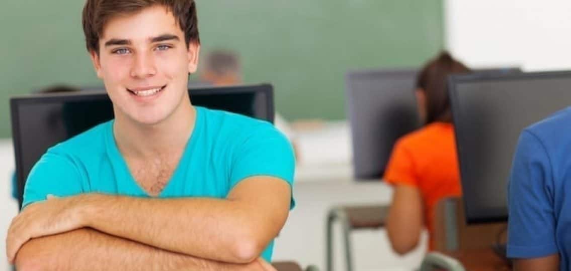 a college student in a computer lab smiling at the camera