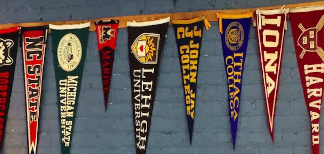 college banners hanging from a wall: Harvard, IONA, Ithaca College, John Jay College, Lehigh University, Marist, Michigan State University, NC State
