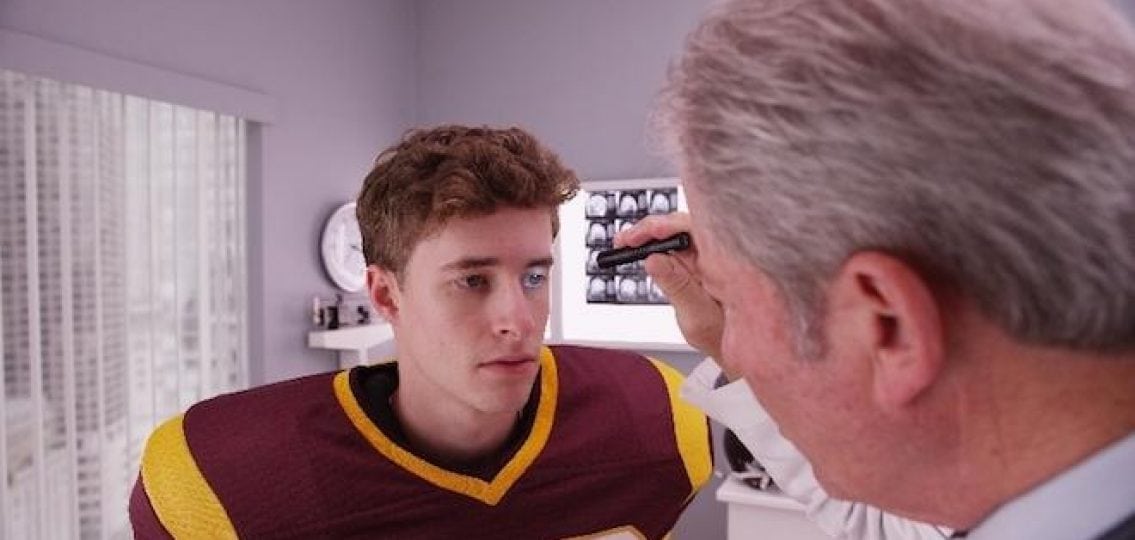 doctor testing a teenage athlete football player for a concussion