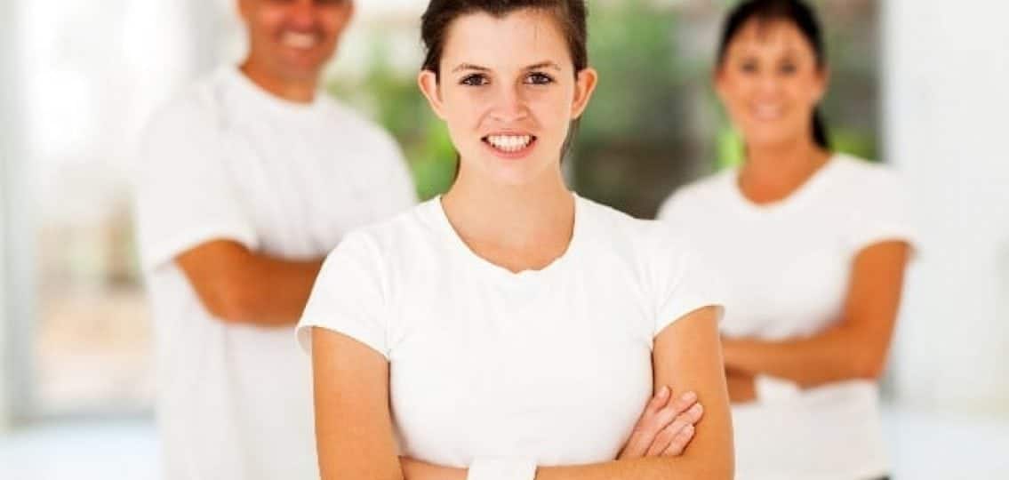 confident teen girl smiling with parents behind her