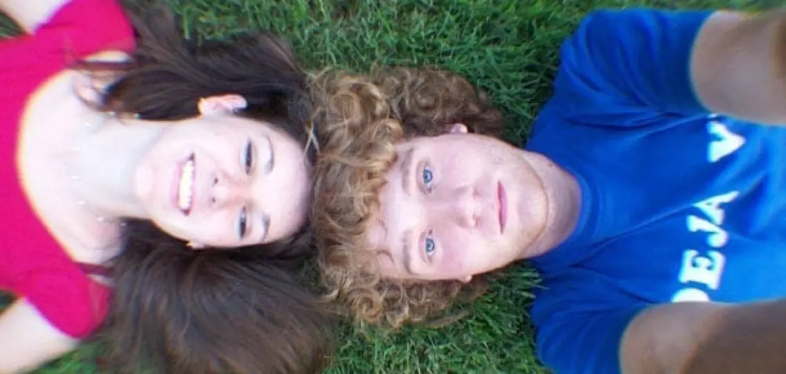 teen couple taking a selfie lying in the grass