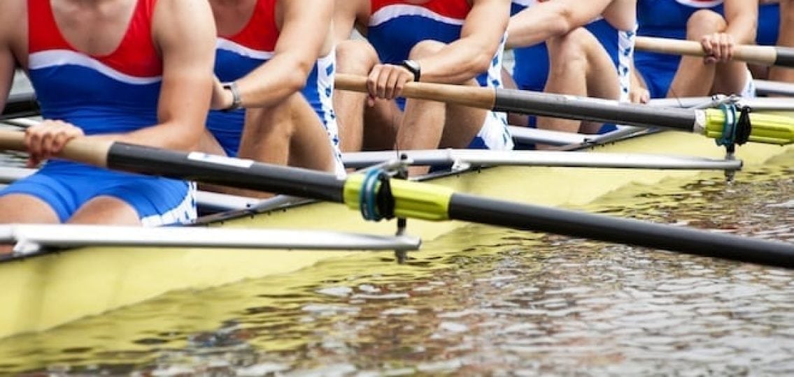 high school rowing team cropped to not see faces rowing a yellow boat