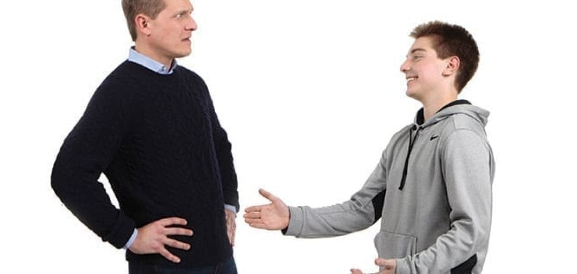 annoyed man looking at teen boy reaching for an inappropriately timed hug