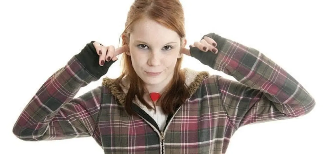 defiant teen girl smirking and covering her ears