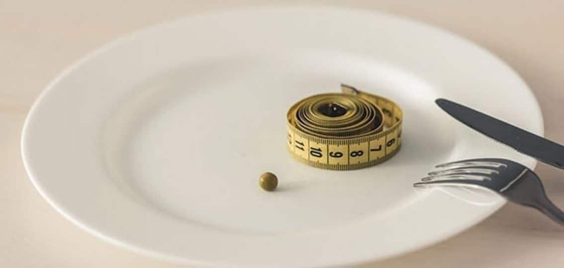 a plate with a single pea and measuring tape to represent eating disorders