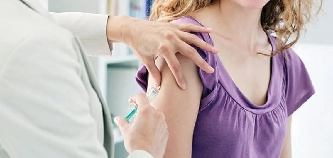 teenage girl getting a vaccine in her arm from a doctor