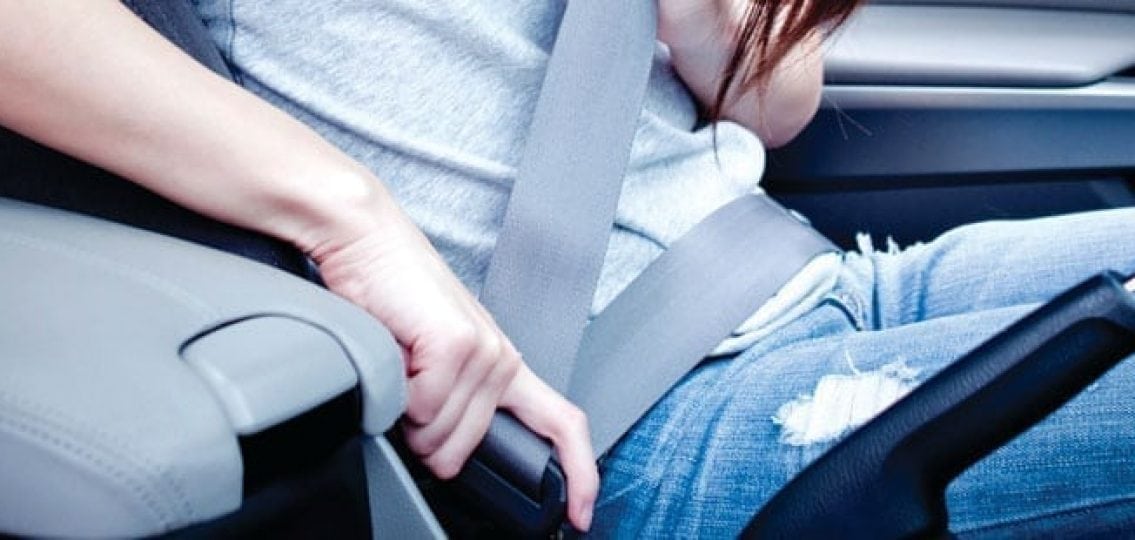teenage girl putting her seatbelt on sitting in the drivers seat