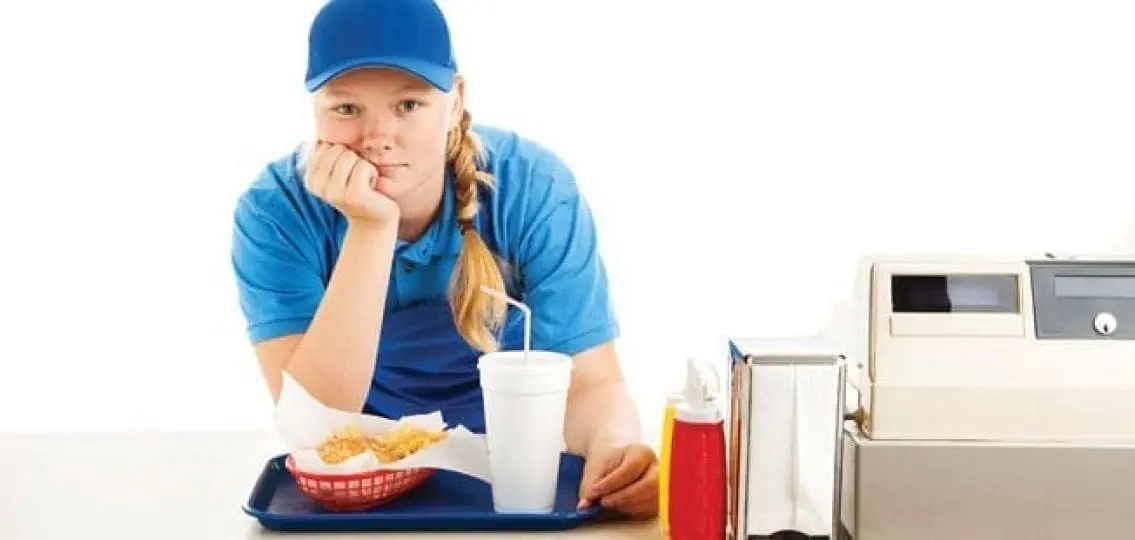 teenage girl working a fast food job holding a tray of food and looking bored