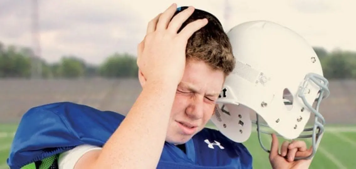 teenage football player grabbing head with concussion