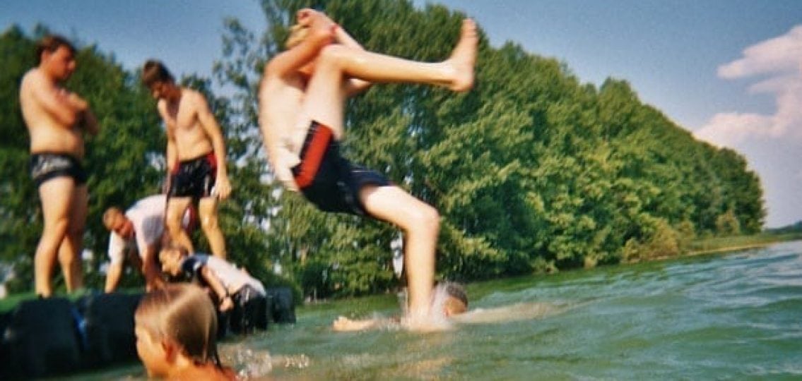 teen boys on summer vacation jumping into a lake