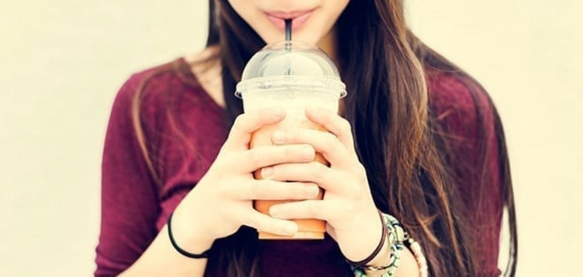 teenage girl drinking a cold coffee drink