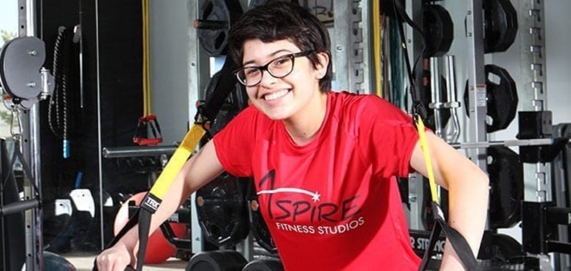 teen girl using exercise equipment to work out wearing a red shirt