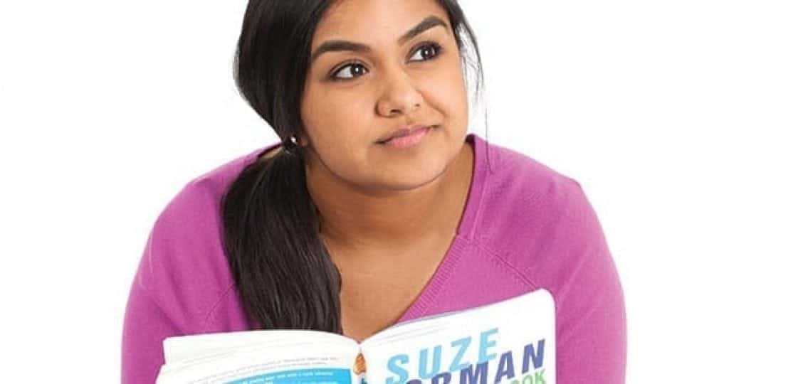 teen girl reading a book on money and thinking