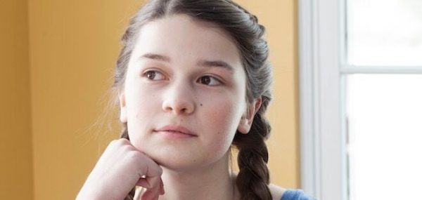 pensive teen girl by a window thinking