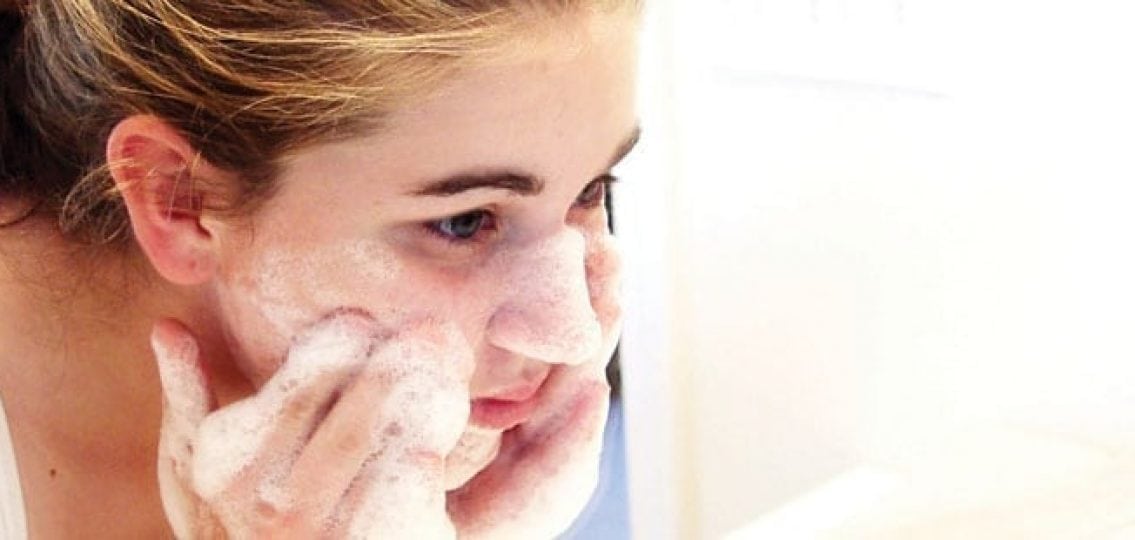 teenage girl washing her face with soap