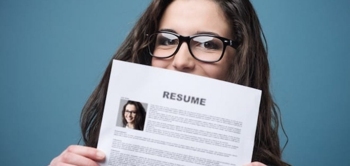 teenage girl holding up her resume blue background
