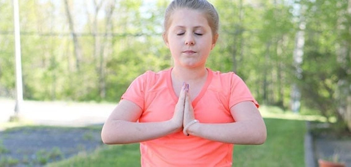 teen girl doing yoga outside eyes closed relaxing