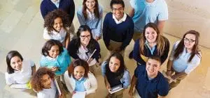 overhead group of teenage high schoolers holding homework and looking up toward the camera