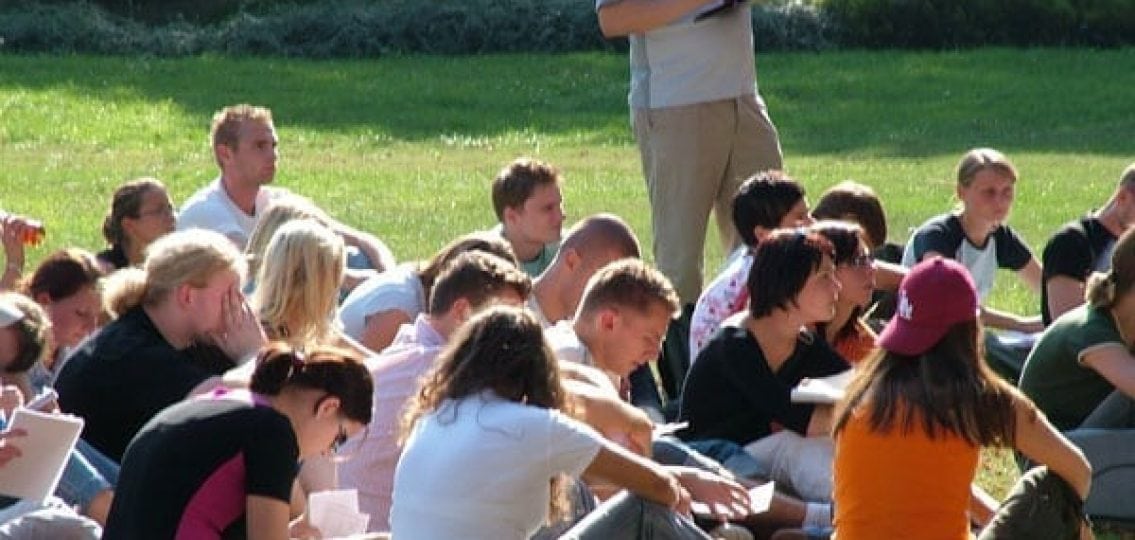 outdoor classroom full of college students listening to a teacher