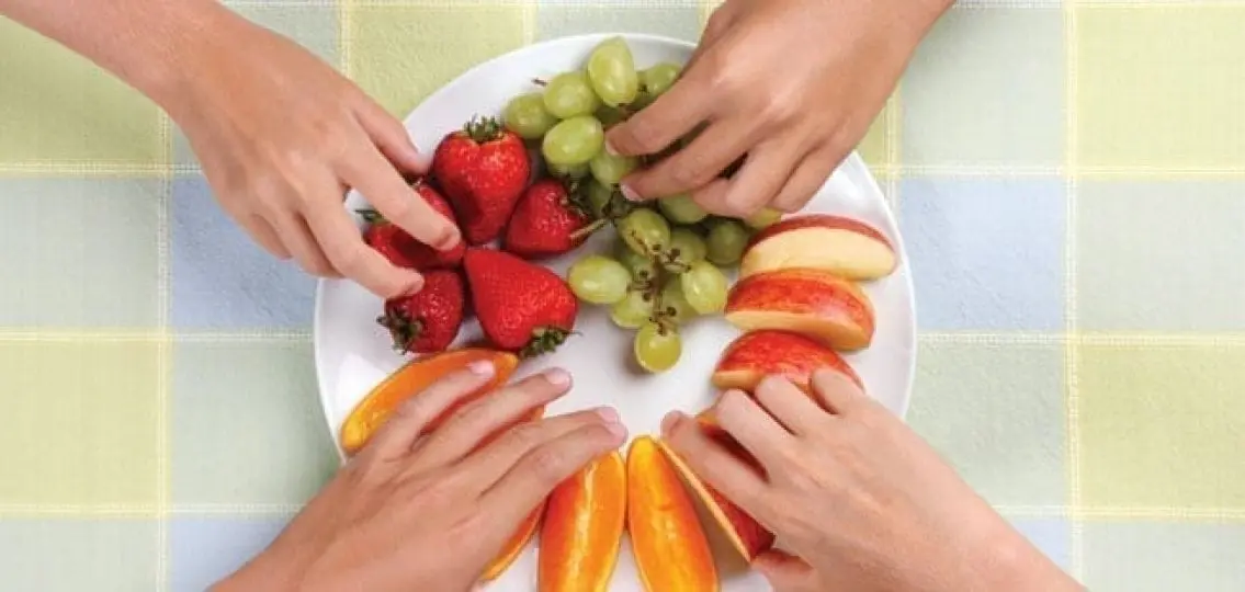hands grabbing a plate full of healthy fruit