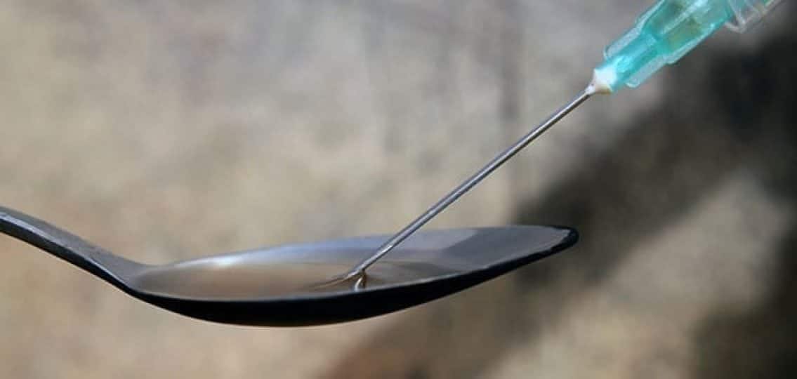 close up of heroin on a spoon with a needle dipped in