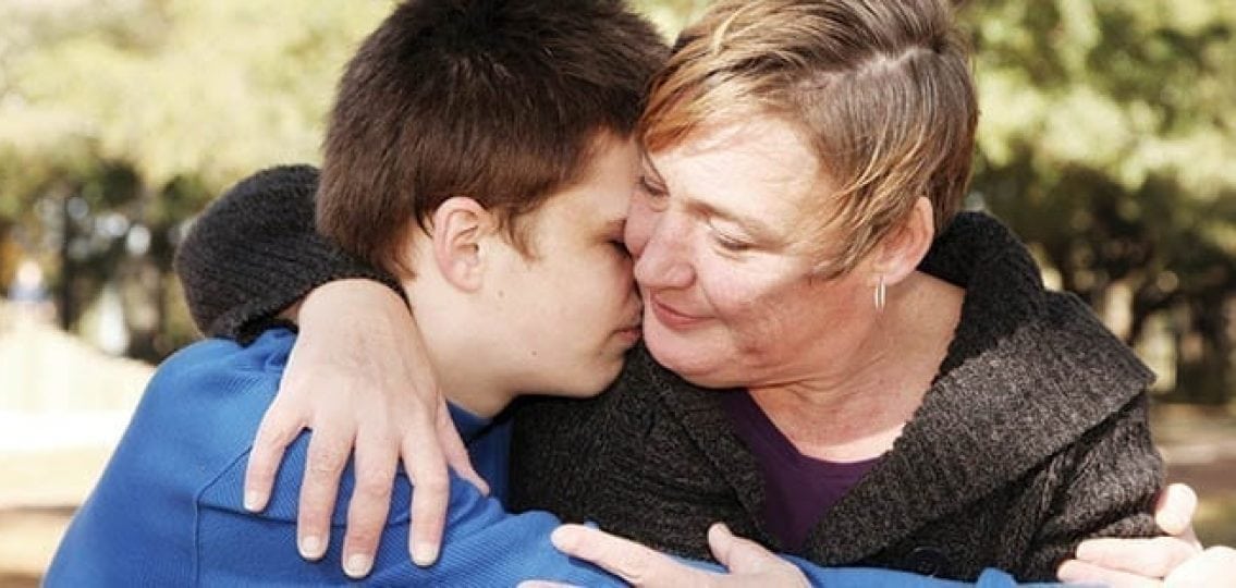 a mom hugging her sad teenage son outdoors