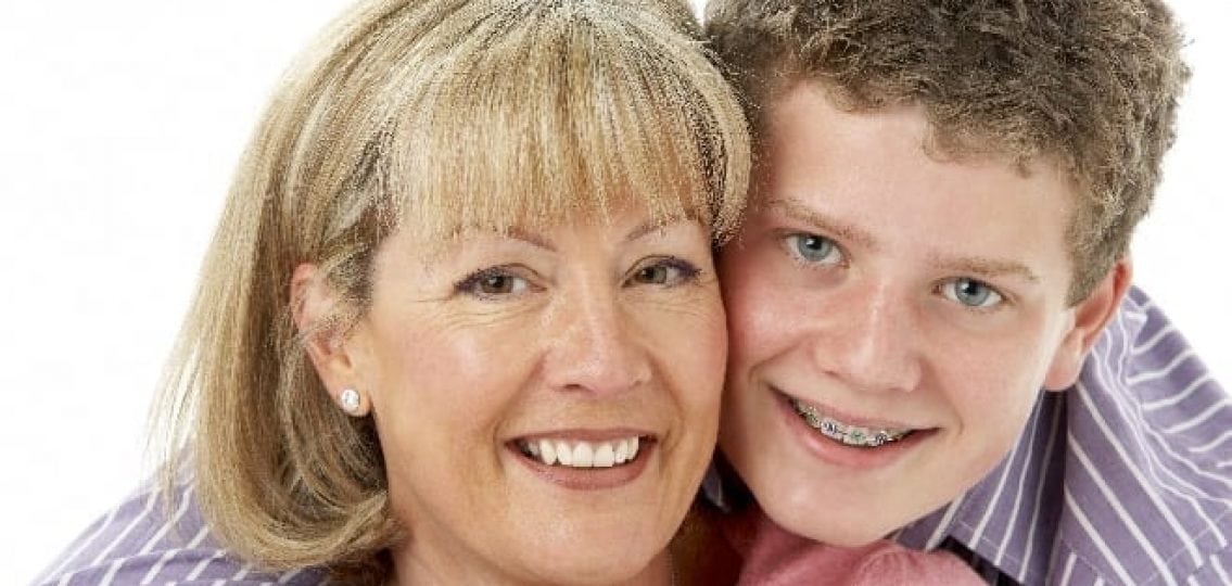 a teenage boy with braces hugging his mother