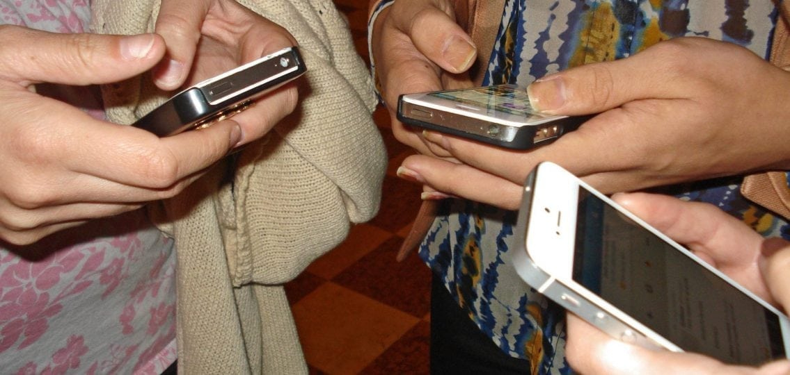 teens standing in a circle and texting close up