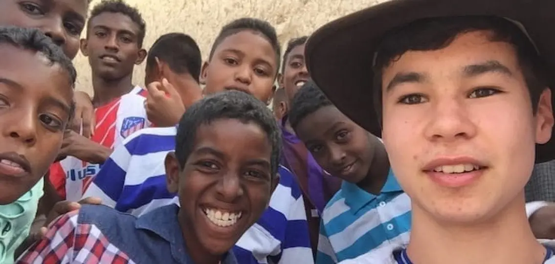author's son taking a selfie with a large group of teens in africa