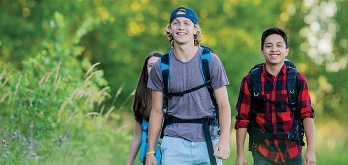 teenagers hiking outdoors in the forest with backpacks