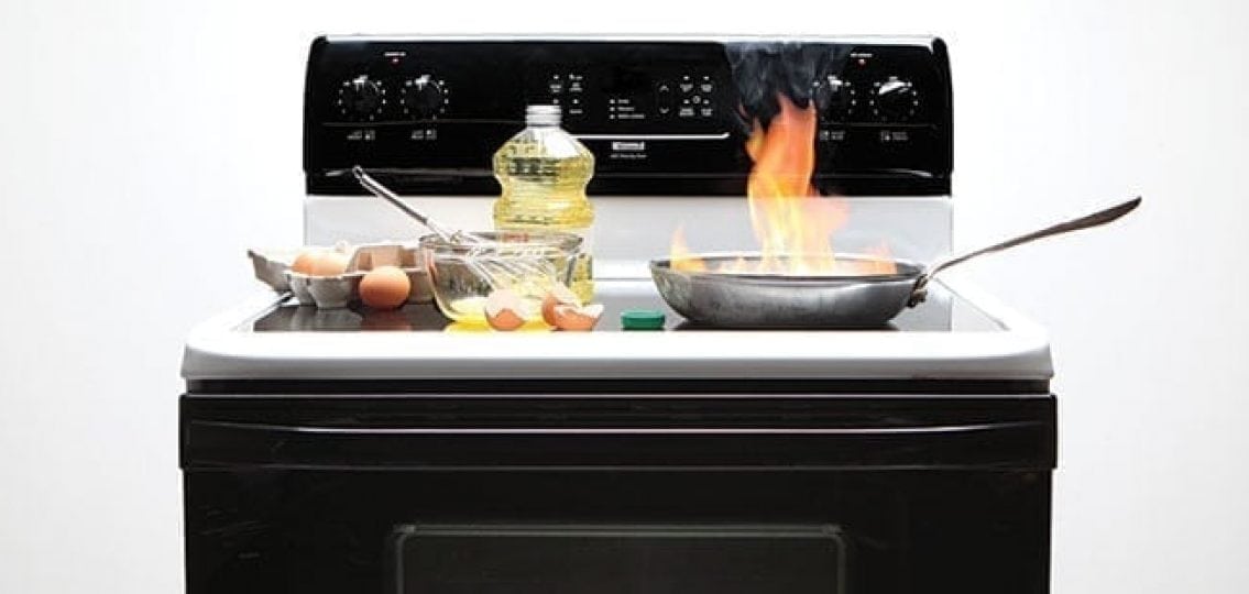kitchen fire pan on stove with flames surrounded by cooking utensils