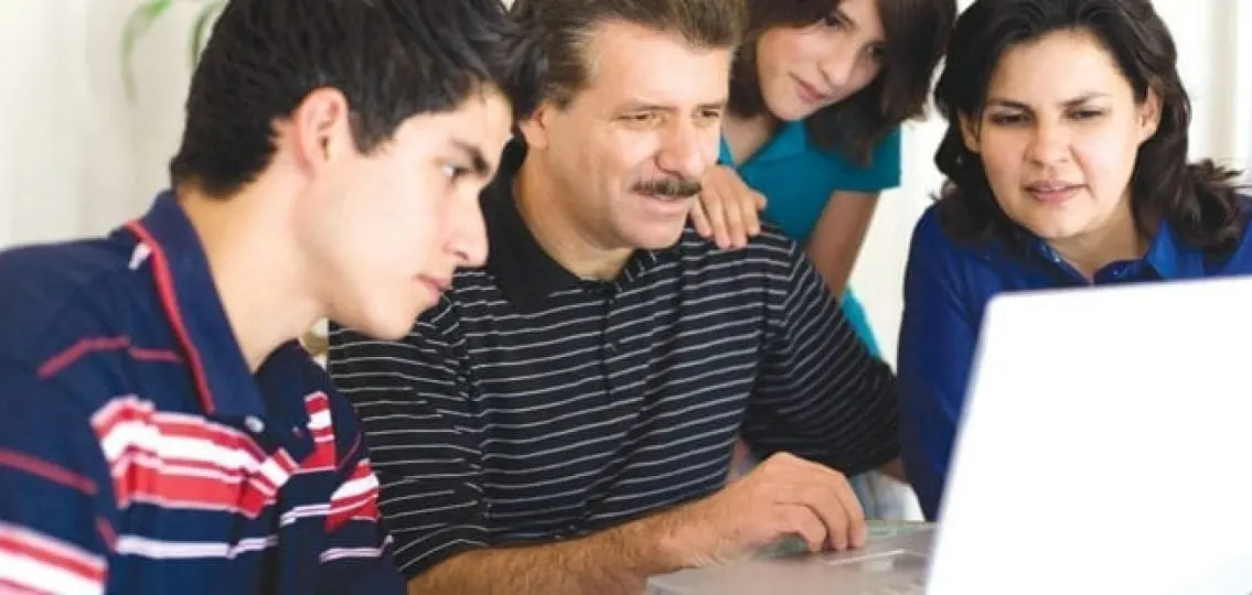 family gathered around a laptop frowning at the screen