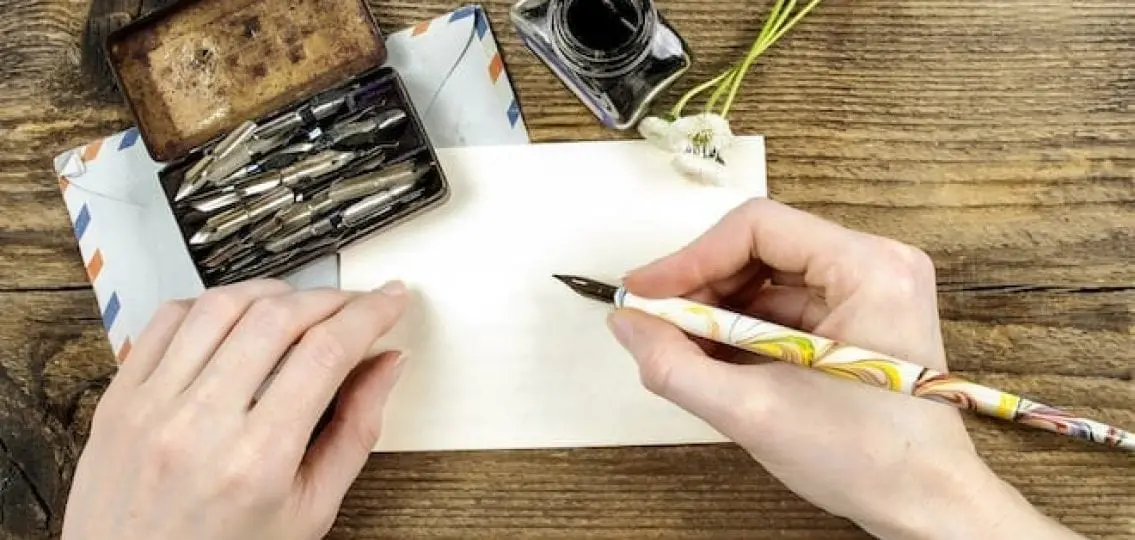 hands writing a letter with an old fashioned pen