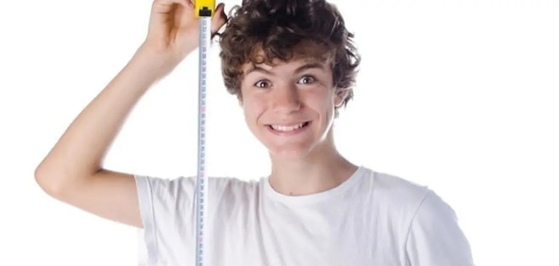 excited teenage boy with measuring tape seeing how tall he is