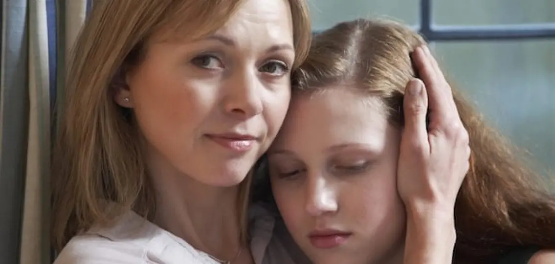 mom hugging and comforting upset teen daughter